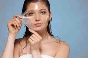 Woman peeling off a facial mask for skin care